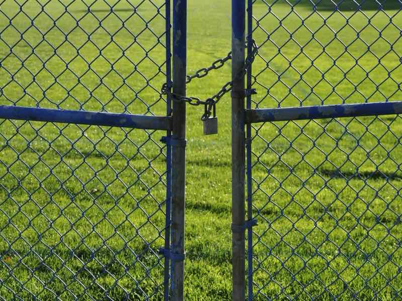 Chain link double gate opening onto a grassy yard